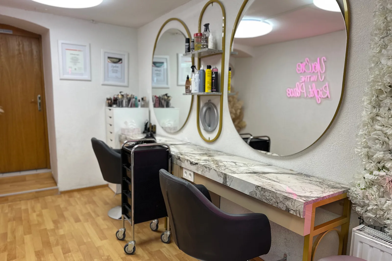 Bedienplatz im Salon mit Marmorkonsole, zwei großen Goldspiegeln und Produktregal